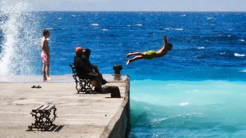Νεαρός πηδάει σε θάλασσα με δύο χρώματα από προβλήτα, με κύματα και…
