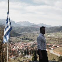 Καλάβρυτα: Αντίδραση του Κασσελάκη για τη σύμπτυξη τμημάτων στο Δημοτικό σχολείο 1 Ο Στέφανος Κασσελάκης με φόντο τα Καλάβρυτα και την ελληνική σημαία.