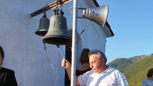 Τίμησαν την Παναγιά στην κορυφή του βράχου της Κέρτεζης ΦΩΤΟ 12 Άνδρας χτυπάει καμπάνα εκκλησίας, με μεγάφωνο και βουνά στο φόντο.
