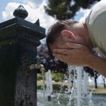 Άνδρας δροσίζεται από τη ζέστη πλένοντας το πρόσωπό του σε δημόσια…