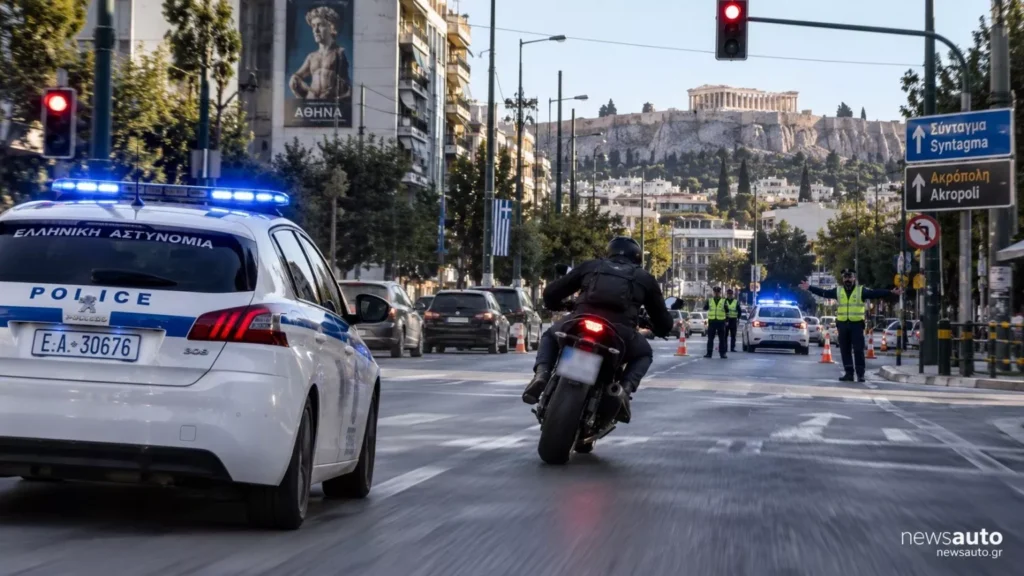 Αστυνομικό όχημα με φάρο, μοτοσικλετιστής και τροχονόμοι σε δρόμο …