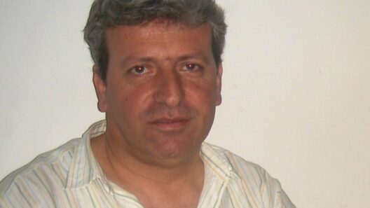 Πορτρέτο του Δημήτρη Καρτέρη με γκρίζα μαλλιά και ριγέ πουκάμισο.