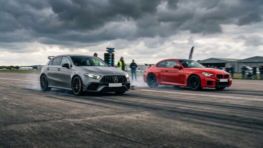 Γκρι Mercedes-AMG A45 και κόκκινη BMW M2 σε αγώνα drag, με καπνό από τα ελαστικά.