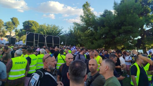 Πλήθος ανδρών με κίτρινα γιλέκα ΠΟΑΣΥ σε εξωτερική συγκέντρωση, με…
