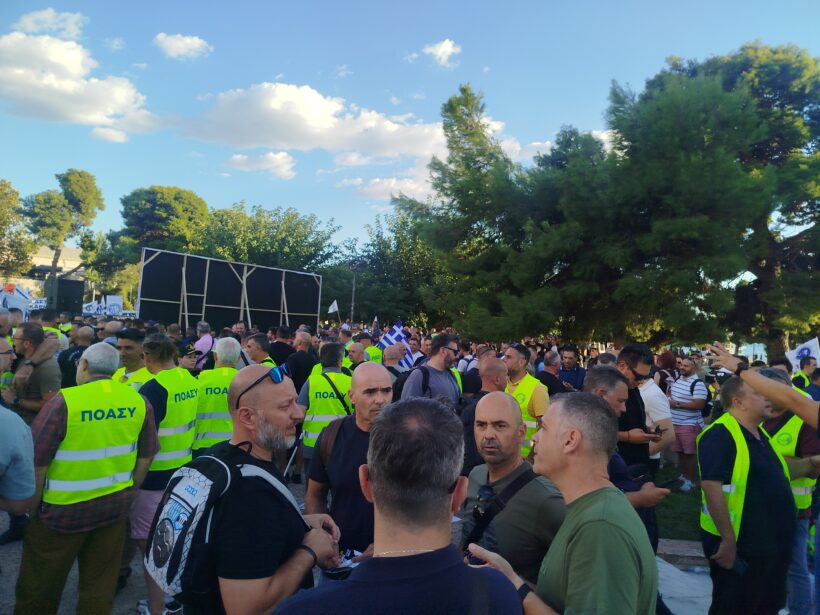 Πλήθος ανδρών με κίτρινα γιλέκα ΠΟΑΣΥ σε εξωτερική συγκέντρωση, με…