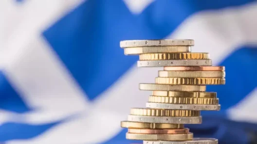 Στοίβες κερμάτων ευρώ μπροστά από την ελληνική σημαία, που αντιπρο…